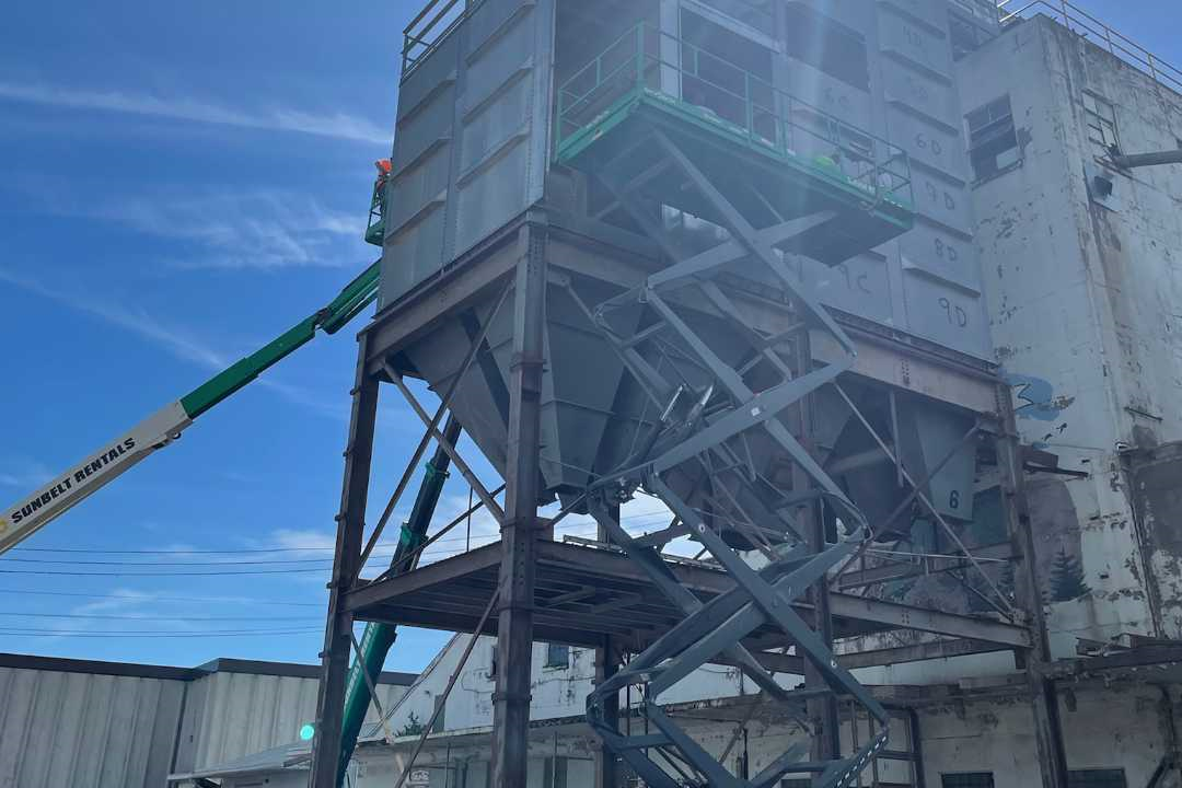 Millwright accessing a large elevated hopper using a boom lift for structural repair or maintenance work