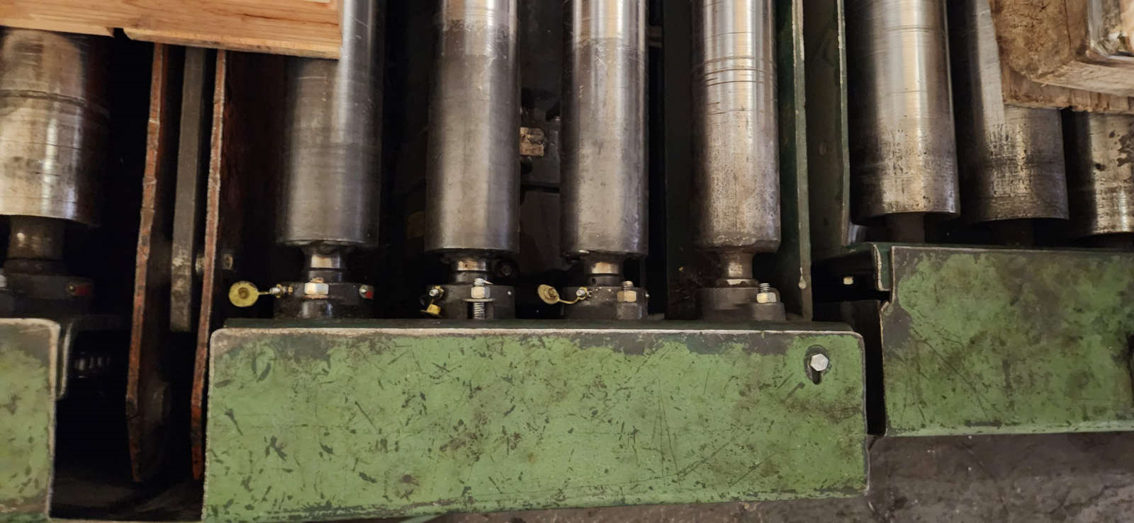 Close-up view of worn industrial rollers on a production line with visible buildup and wear marks.