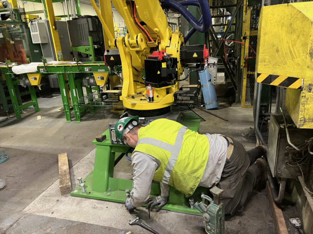 Lovegreen millwright securing the base of a newly installed robotic arm inside a production facility.