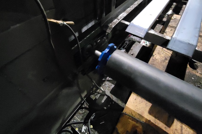 Close-up of a new conveyor shaft being installed with a blue bearing housing during a maintenance project.